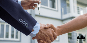 a home in the background with two people shaking hands and handing over a home key